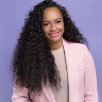 Image of Kathleen in a pink blazer in front of a lilac wall